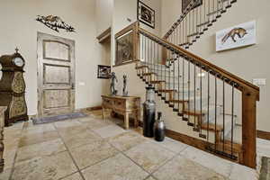 Entrance foyer featuring stone tile floors and a towering ceiling