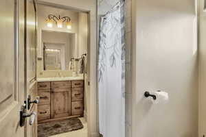 Full bathroom with vanity, a shower with shower curtain, and light tile patterned floors