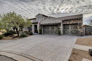 Mediterranean / spanish house featuring a garage, concrete driveway, stone siding, a tile roof, and stucco siding