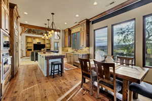 Kitchen with hanging light fixtures, a kitchen island, decorative backsplash, light stone countertops, and recessed lighting