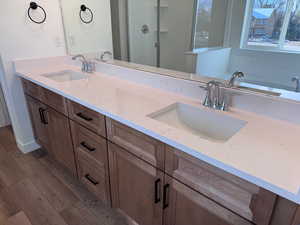 Bathroom with double vanity, a shower stall, light wood-type flooring, and a bath