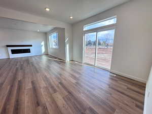 Unfurnished living room with wood finished floors, a fireplace, a textured ceiling, and recessed lighting