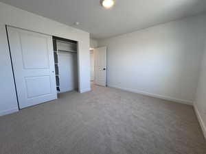 Unfurnished bedroom featuring a textured ceiling, light carpet, and a closet