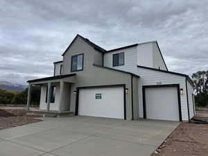 View of front of property with covered porch, driveway, and an attached garage