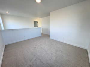 Carpeted spare room featuring baseboards