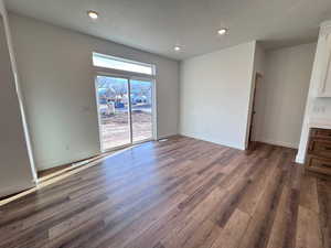 Unfurnished living room with dark wood-type flooring, recessed lighting, and a textured ceiling