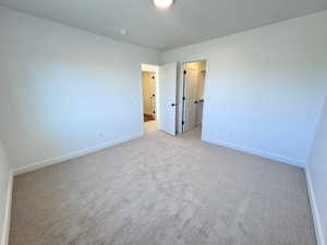 Unfurnished bedroom with a spacious closet and carpet