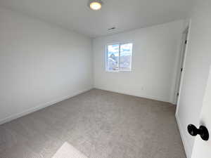 Empty room featuring light colored carpet and baseboards