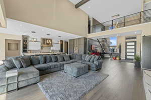 Living room with a towering ceiling, stairway, light wood-type flooring, and recessed lighting