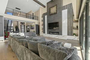 Living room featuring a high ceiling, a high end fireplace, and light wood-style floors