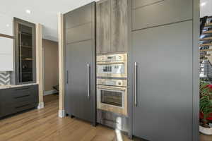Kitchen featuring modern cabinets, gray cabinetry, recessed lighting, stainless steel double oven, and light wood-type flooring