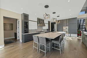 Kitchen featuring gray cabinetry, modern cabinets, hanging light fixtures, a kitchen breakfast bar, and a large island with sink