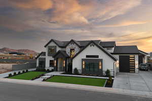 View of front of home with stone siding, concrete driveway, stucco siding, and a garage