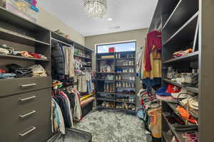 Spacious closet with dark carpet and a chandelier