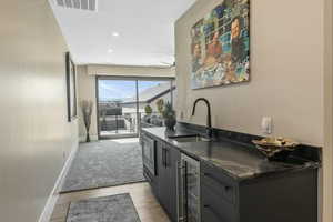 Bar area with wine cooler, gray cabinetry, recessed lighting, light wood-style floors, and stainless steel microwave