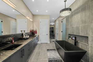 Bathroom featuring double vanity, a soaking tub, recessed lighting, a chandelier, and a spacious closet