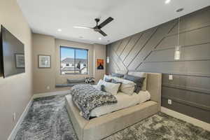 Carpeted bedroom with ceiling fan, an accent wall, and recessed lighting