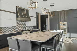 Kitchen with a breakfast bar area, modern cabinets, extractor fan, a spacious island, and light stone countertops
