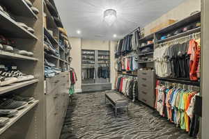 Walk in closet featuring dark colored carpet and a chandelier
