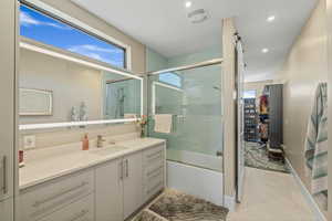 Bathroom with combined bath / shower with glass door, plenty of natural light, a spacious closet, vanity, and recessed lighting
