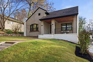 View of front of property with a front lawn, a shingled roof, and covered porch