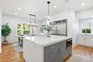 Kitchen featuring gray cabinets, pendant lighting, a kitchen island, built in appliances, and white cabinetry