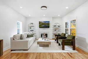 Living area with a high end fireplace,  wood finished floors, built in features, and recessed lighting