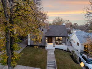 View of front of home featuring a shingled roof, a front lawn, a porch, and stucco siding