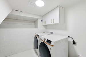 Washroom with washer and clothes dryer and cabinet space