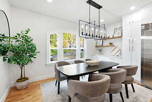 Dining room with light wood finished floors, a chandelier, and recessed lighting