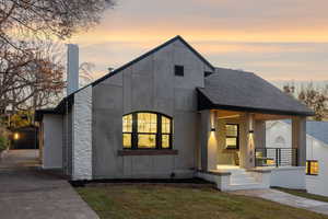 Modern home with a shingled roof, a yard, a porch, and an outdoor structure