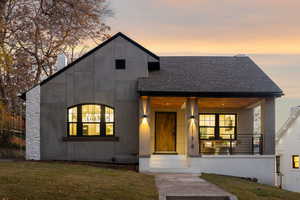 Modern home with a lawn, covered porch, and a shingled roof
