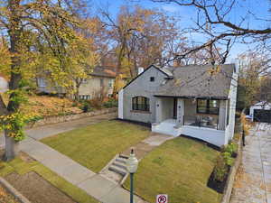 View of front of property with a front lawn, a shingled roof, and a porch
