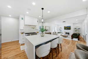 Kitchen featuring white cabinetry, open floor plan, a kitchen breakfast bar, and recessed lighting