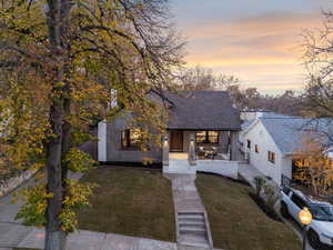 View of front of house featuring a porch, a lawn, and a shingled roof