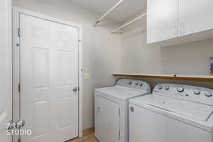 Laundry area with cabinet space, washer and dryer, and light tile patterned floors