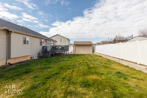 Fenced backyard featuring a storage shed and a deck