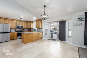 Kitchen featuring lofted ceiling, appliances with stainless steel finishes, pendant lighting, light countertops, and a peninsula