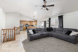 Living area featuring vaulted ceiling, light tile patterned flooring, a ceiling fan, and a chandelier