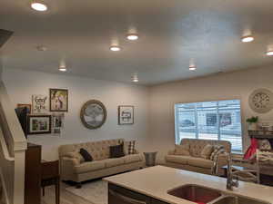 Living area with light wood-type flooring and recessed lighting