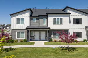 View of front of home featuring board and batten siding, a front lawn, roof with shingles, and covered porch