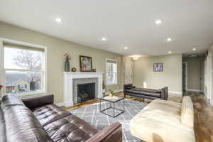 Living area with recessed lighting, a tiled fireplace, and wood finished floors