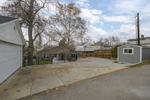 View of front of house with a garage, a residential view, a patio area, and a storage shed