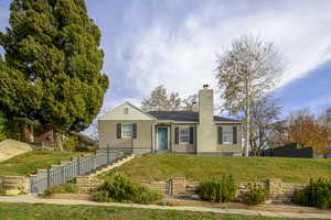View of front of property featuring a front yard, a chimney, and stairs