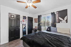 Bedroom featuring dark wood-type flooring, multiple closets, and a ceiling fan