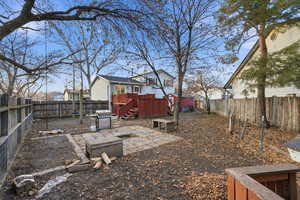 Fenced backyard featuring a patio, a wooden deck, stairs, and a storage unit