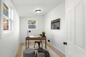 Office space with lofted ceiling and light wood-style flooring