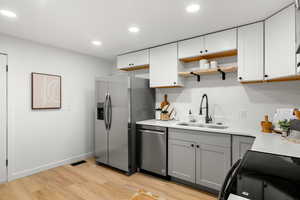 Kitchen featuring open shelves, gray cabinetry, black range with electric cooktop, dishwasher, and light stone counters