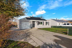 Single story home with roof mounted solar panels, concrete driveway, and a garage