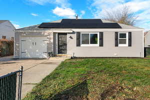 View of front of home with driveway, a garage, solar panels, and a shingled roof